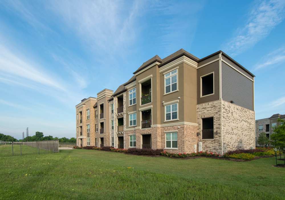 Exterior view of the community with green lawn at Orleans at Fannin Station in Houston, Texas
