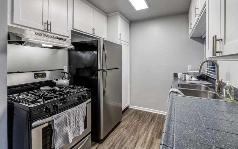 Renovated kitchen with white cabinets and black and stainless steel appliances at Kendallwood Apartments in Whittier, California