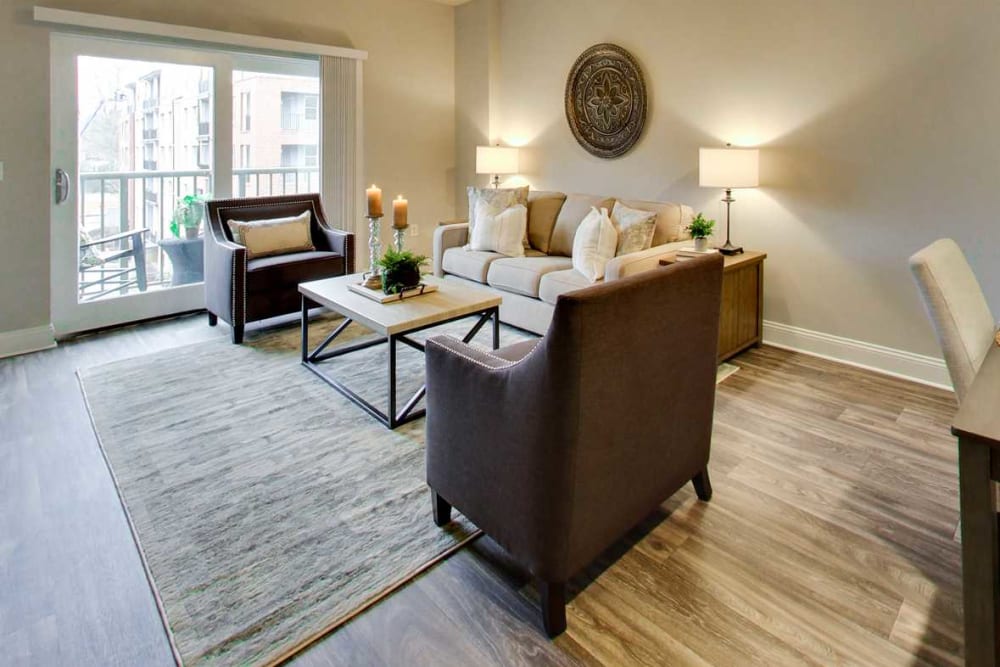 Spacious living and dining areas with wood-style flooring opening onto a private balcony at SouthPark Morrison in Charlotte, North Carolina