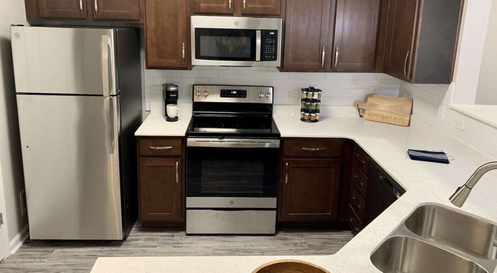 Kitchen with wooden cabinets, refrigerator, microwave and stainless-steel sink at Preserve At Columbus Park in Columbus, Georgia
