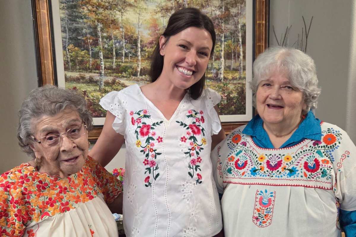 Two residents and a staff member in colorful Mexican dresses pose for a photo at Isle at Cedar Ridge in Cedar Park, Texas.
