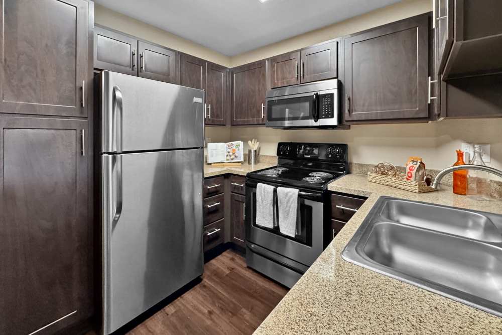 Renovated kitchen with brown cabinets and stainless steel appliances at Tuscany Village Apartments in Ontario, California