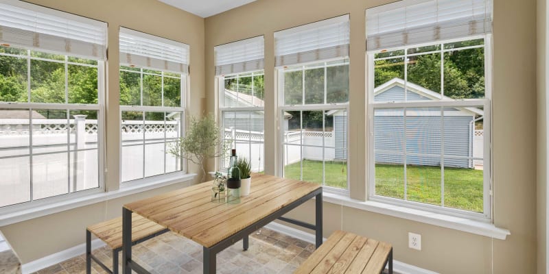 A dining room with large windows viewing the backyard of a home at Columbia Colony in Patuxent River, Maryland