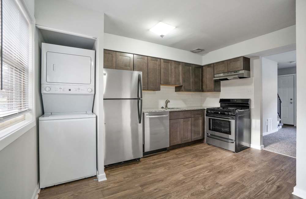 Modern kitchen with stainless steel appliances, granite countertops, wood-style flooring, and in-unit washer and dryer at Fairway Ridge in Baltimore, Maryland
