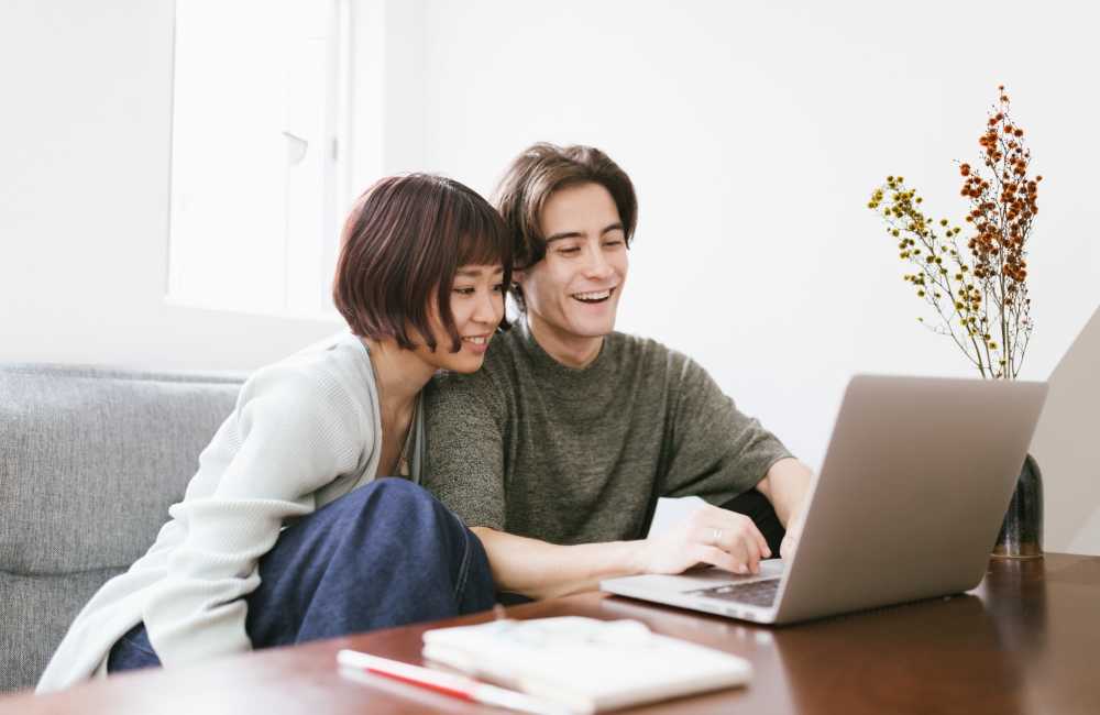 Cozy couple sharing a laptop in a bright living space at Trolley Court in San Diego, California 