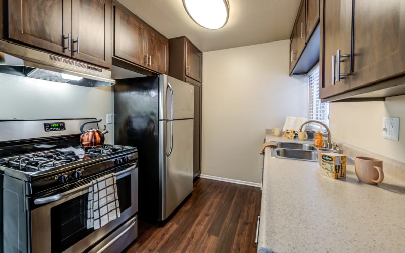 Renovated kitchen with stainless steel appliances and brown cabinets at Kendallwood Apartments in Whittier, California