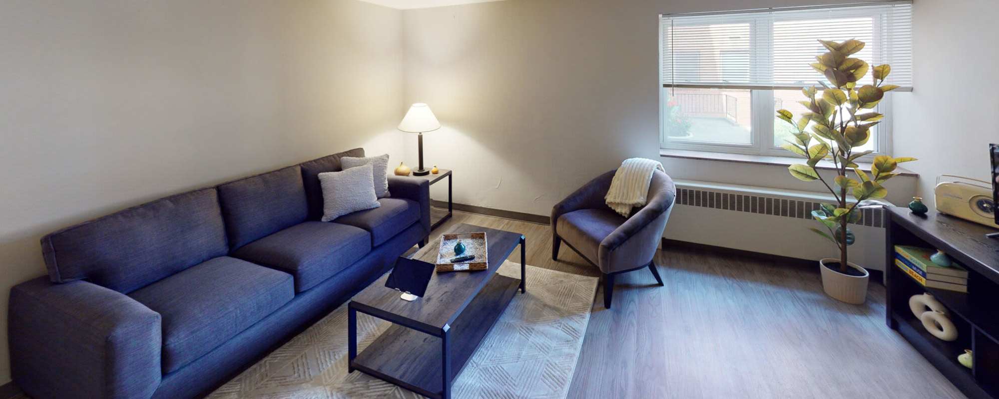 Bright living room with lamp, windows and couch at Lebanon Vue in Pittsburgh, Pennsylvania