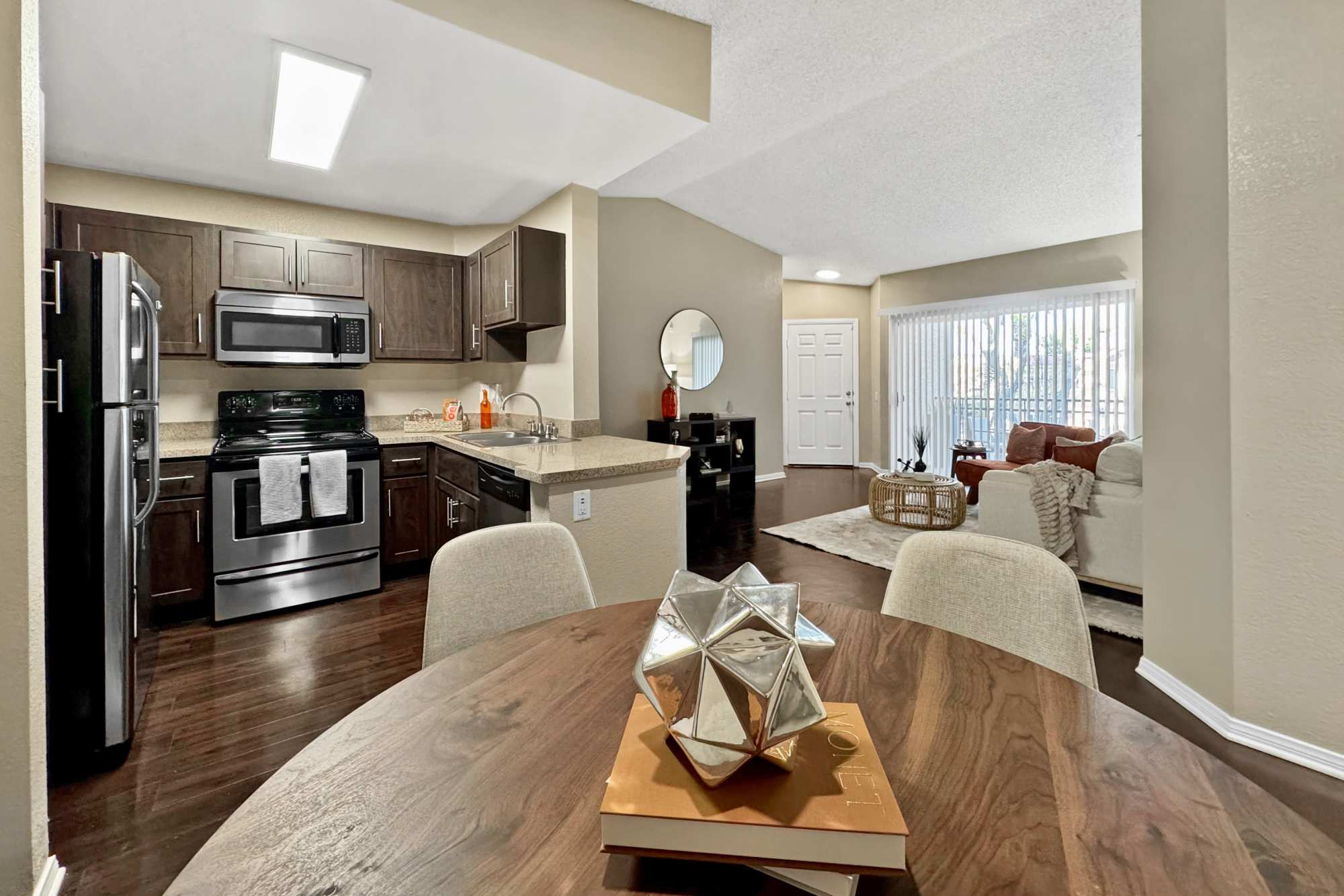 Living room and kitchen with wood-style flooring at Tuscany Village Apartments in Ontario, California