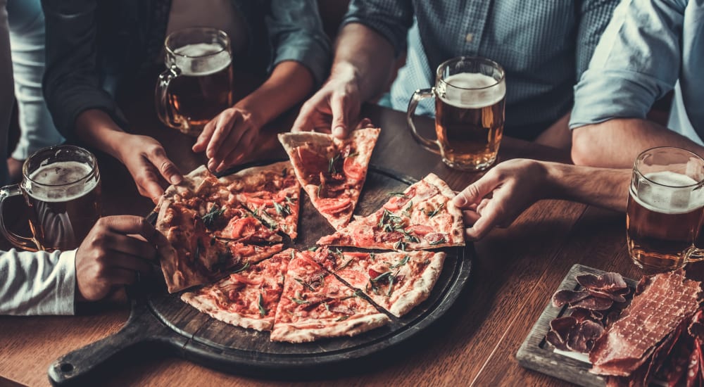 A group of friends sharing a pizza and drinks in a restaurant near Novo Westlake in Jacksonville, Florida