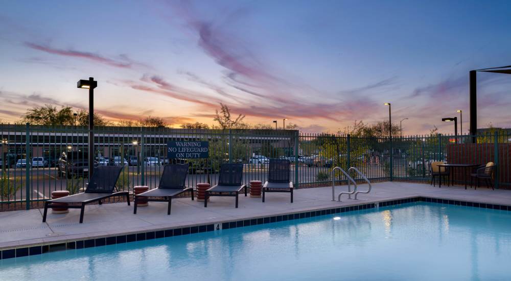 Outdoor swimming pool area at sunset featuring lounge chairs at WaterWalk Phoenix - North Happy Valley in Phoenix, Arizona