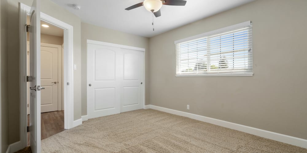 Carpeted bedroom with ceiling fan and closet at Bon Aire Apartments in Castro Valley, California