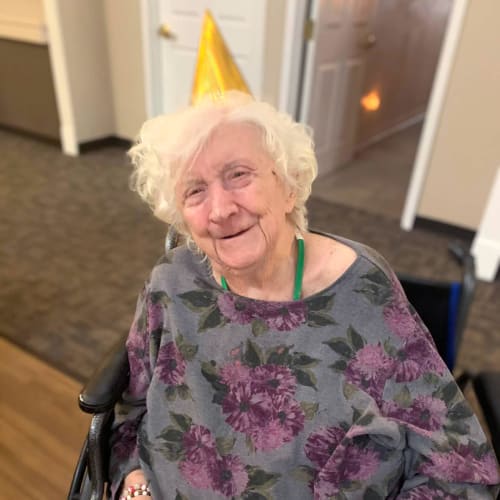 Resident wearing a party hat while holding a cheese and meat spread at Canoe Brook Assisted Living in Broken Arrow, Oklahoma