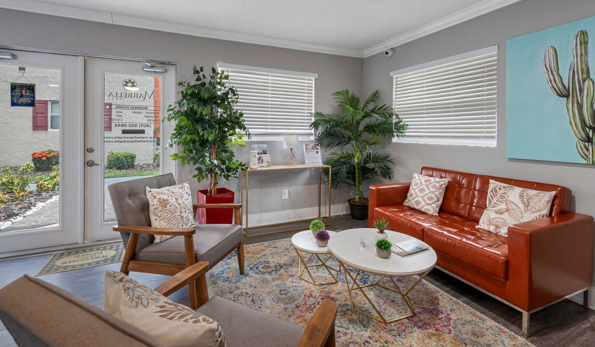Staged living room with modern furniture, large windows, and natural light in Marbella Park in Orlando, Florida
