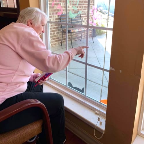 Resident sitting in a chair looking out a window at Oxford Glen Memory Care at Owasso in Owasso, Oklahoma