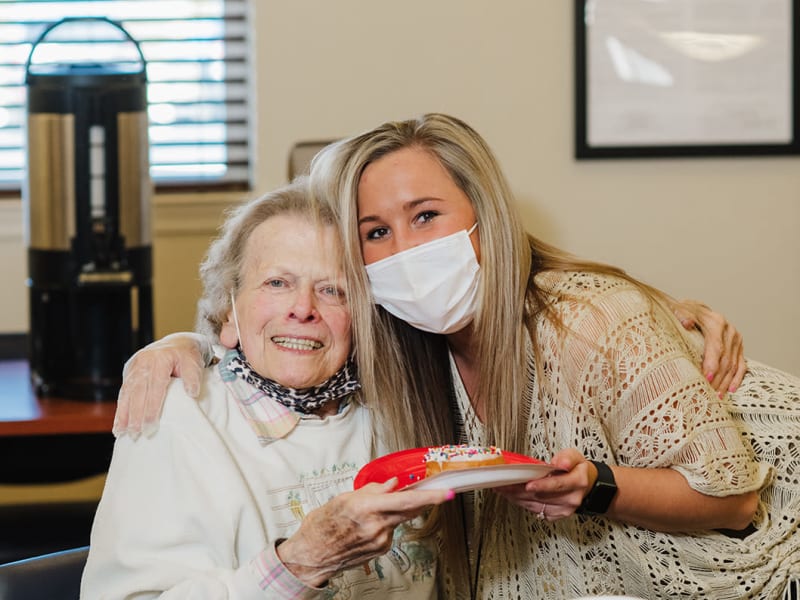 Resident being served a donut on a plate at a English Meadows community