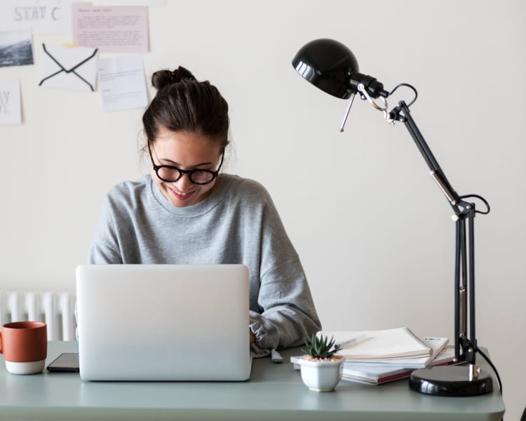 Resident filling out a form on the community's website on her laptop in her home office at Terra Martinez in Martinez, California