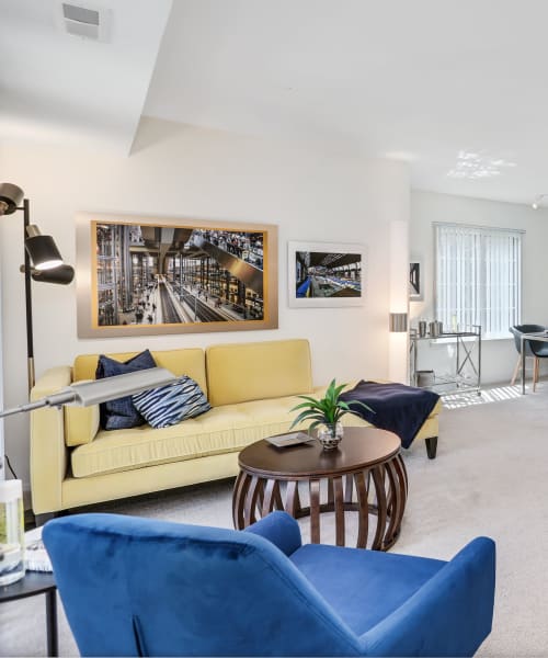 Living room with a sofa and armchair at Saddle Creek Apartments in Novi, Michigan