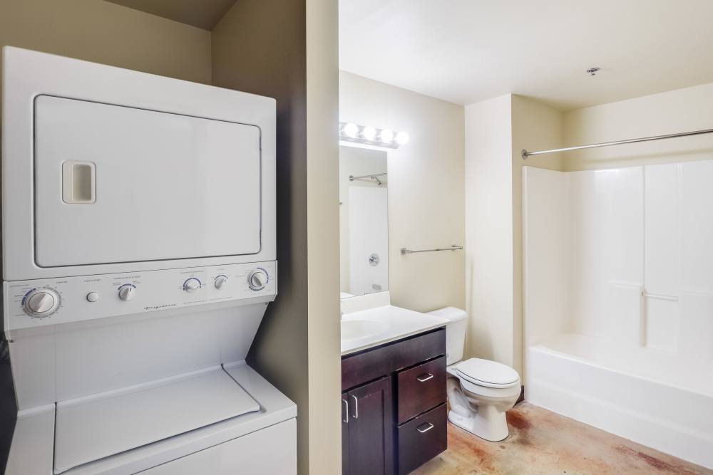 Bathroom with shower, sink, and washer dryer at Rumely Lofts in Des Moines, Iowa