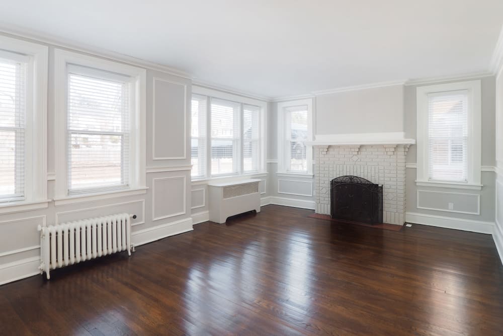 Spacious living room with dark wood floors and white walls with large windows at Packard West Hartford in West Hartford, Connecticut