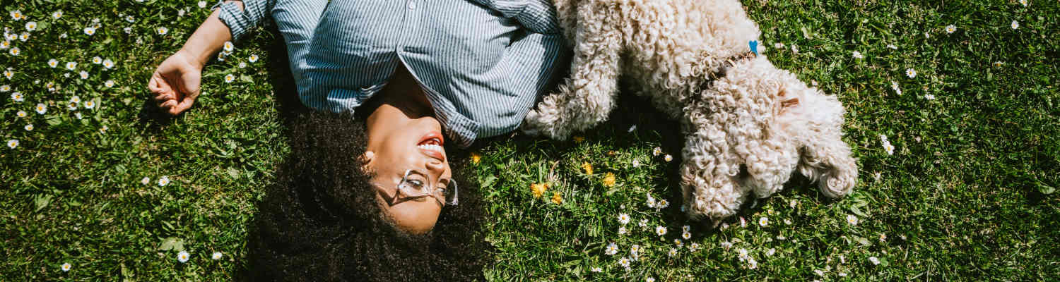Resident and her dog lying in the grass at Carlwynne Manor Apartment Homes in Carlisle, Pennsylvania