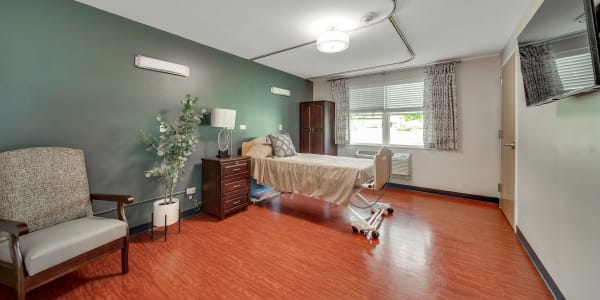 Bedroom with a window right beside the bed and hookups for privacy curtains at Fair Oaks Health Care Center in Crystal Lake, Illinois