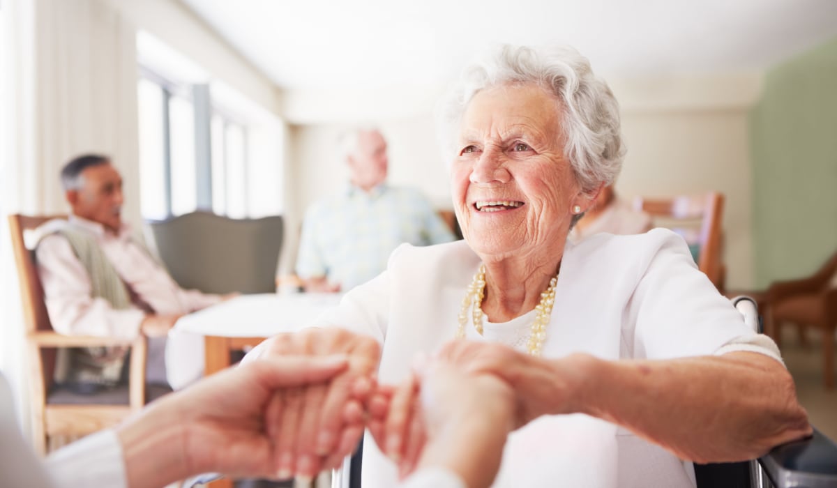 A resident holding hands with a staff member at CERTUS Premier Memory Care Living in Vero Beach, Florida.