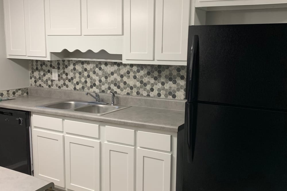 A kitchen with white cupboards and black appliances at Foxwood Apartments in Doraville, Georgia