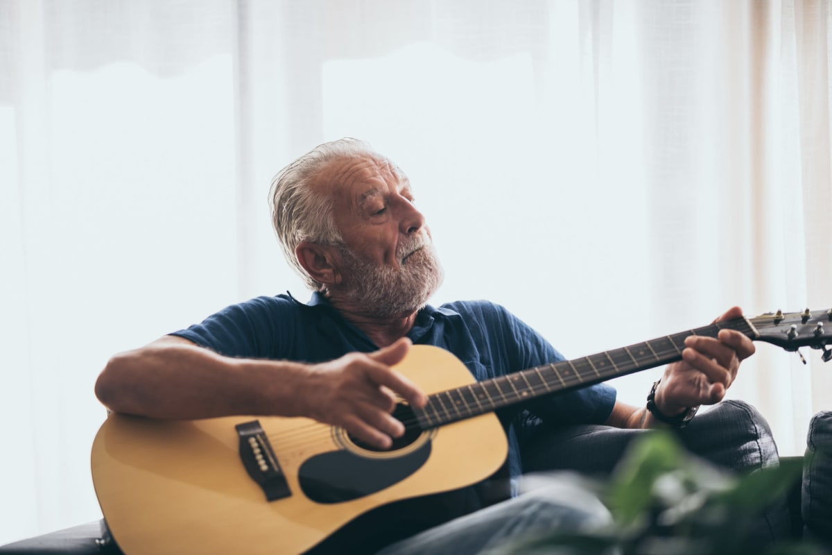 Resident sitting and playing an acoustic guitar at Canoe Brook Assisted Living in Duncan, Oklahoma