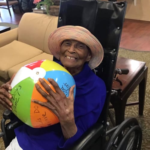 Resident holding a beach ball at Oxford Glen Memory Care at Grand Prairie in Grand Prairie, Texas