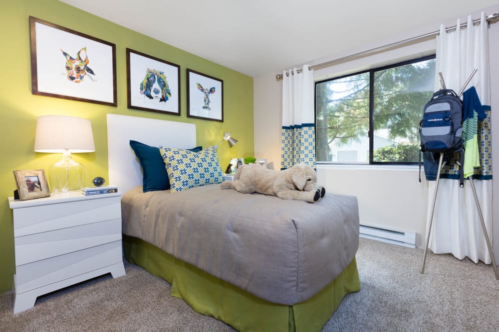 Master bedroom with draped windows and an accent wall in a model home at Madison Sammamish Apartments in Sammamish, Washington