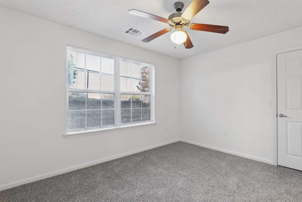 Charming bedroom with elegant ceiling fan and bright windows at Covington Woods Apartments in Lansing, Kansas.