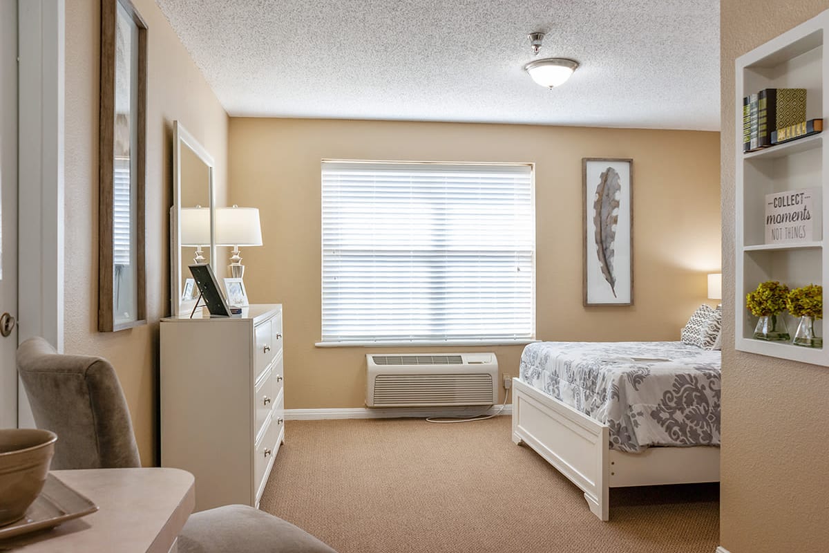 Bedroom of model unit with dresser, bed and chair at Cimarron Place in Midland, Texas