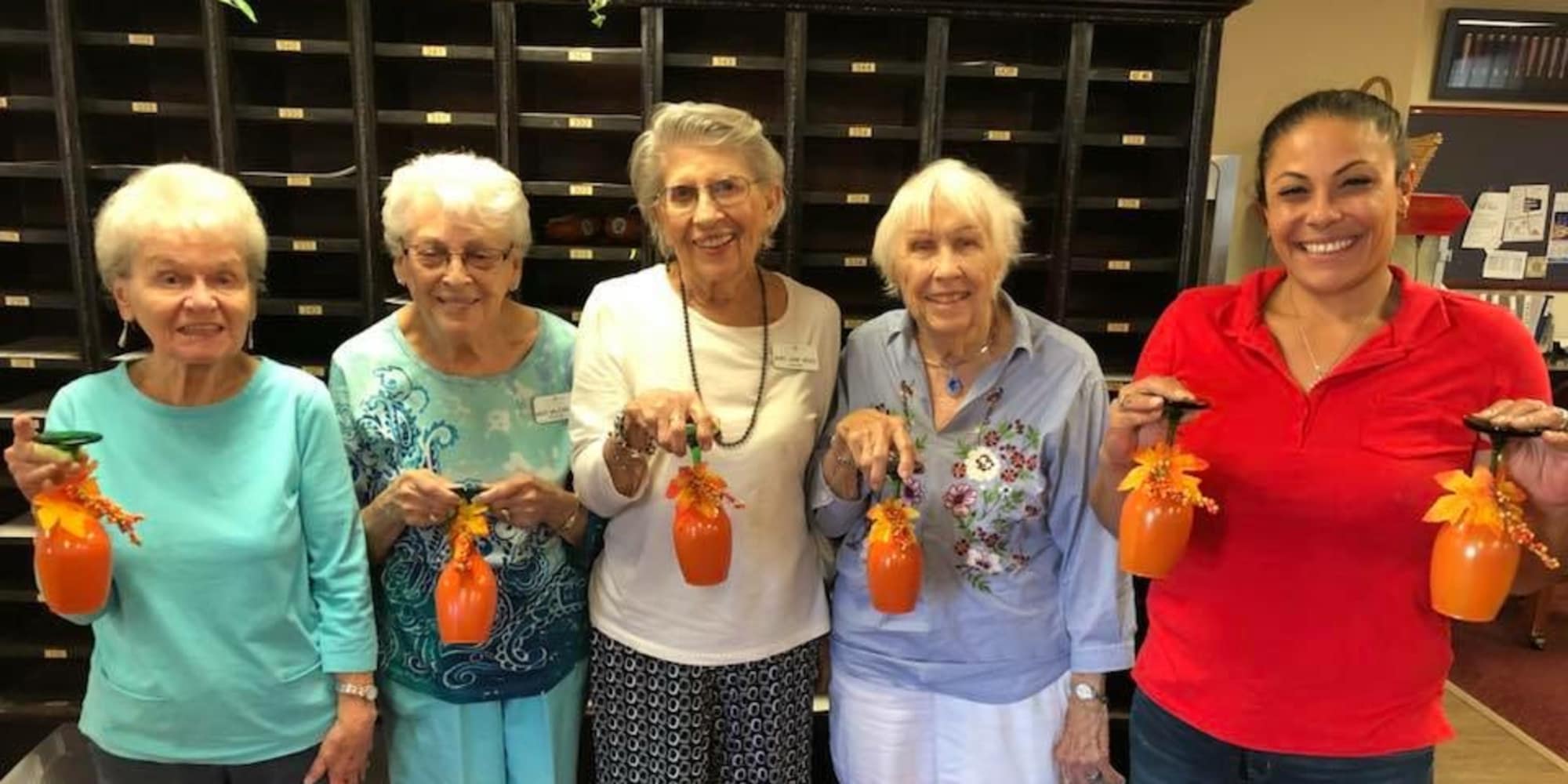 Residents and staff holding decorated cups at Paloma Landing Retirement Community in Albuquerque, New Mexico