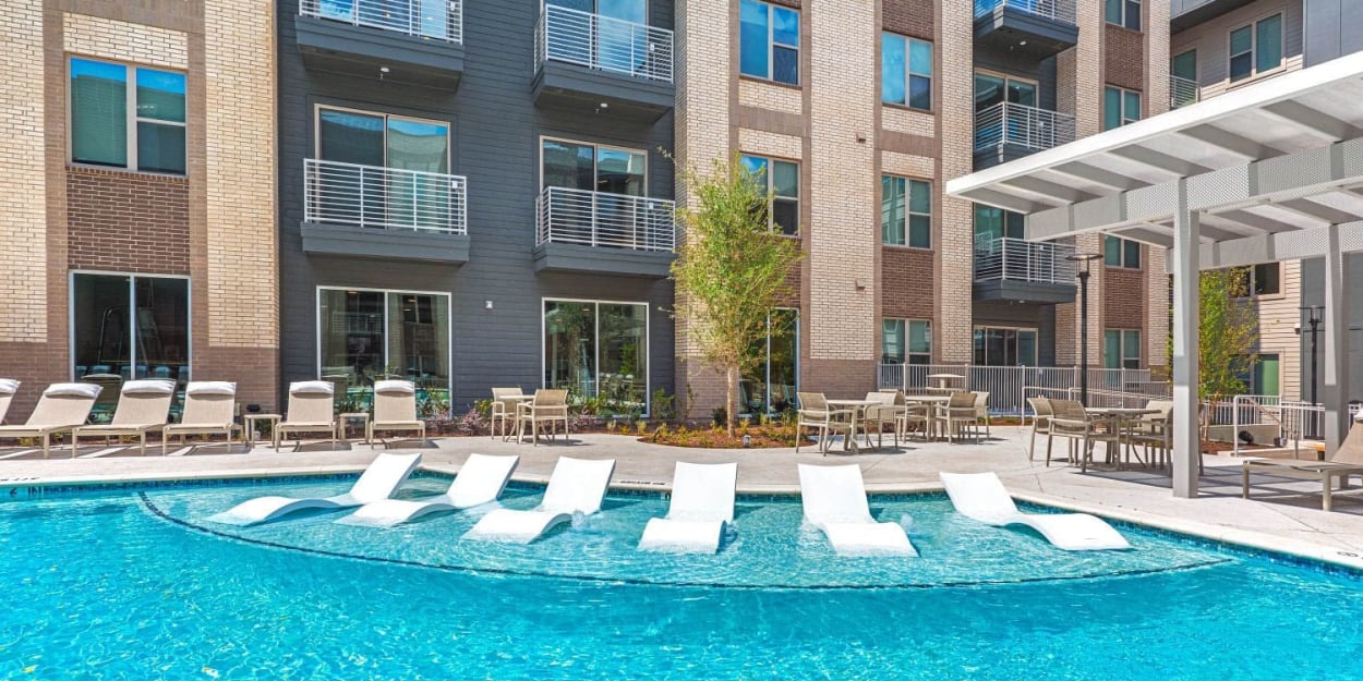 Resort-style swimming pool with in-water lounge chairs at Luxia Preston, Plano, Texas