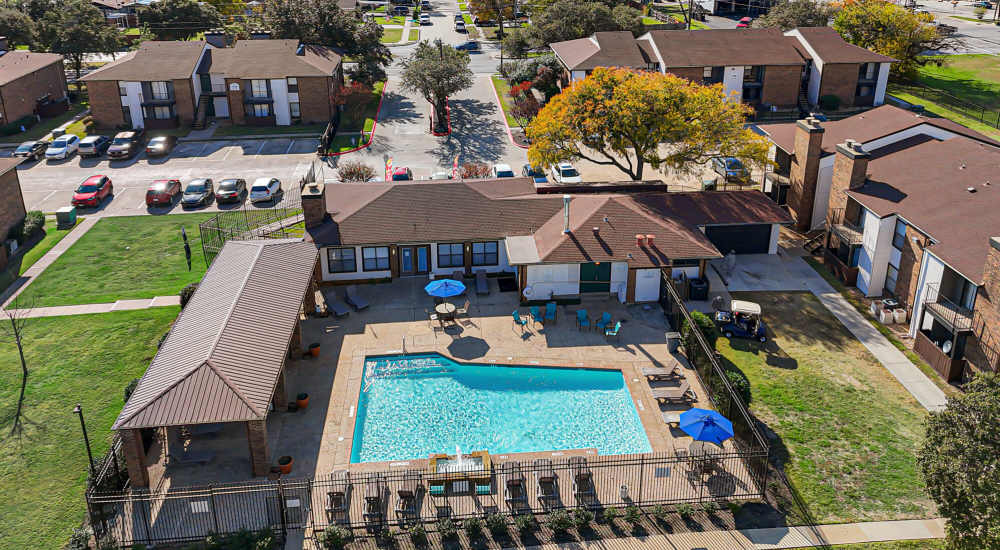 Swimming pool with tanning chairs & pergola at Pine Oaks Apartments in Mesquite, Texas
