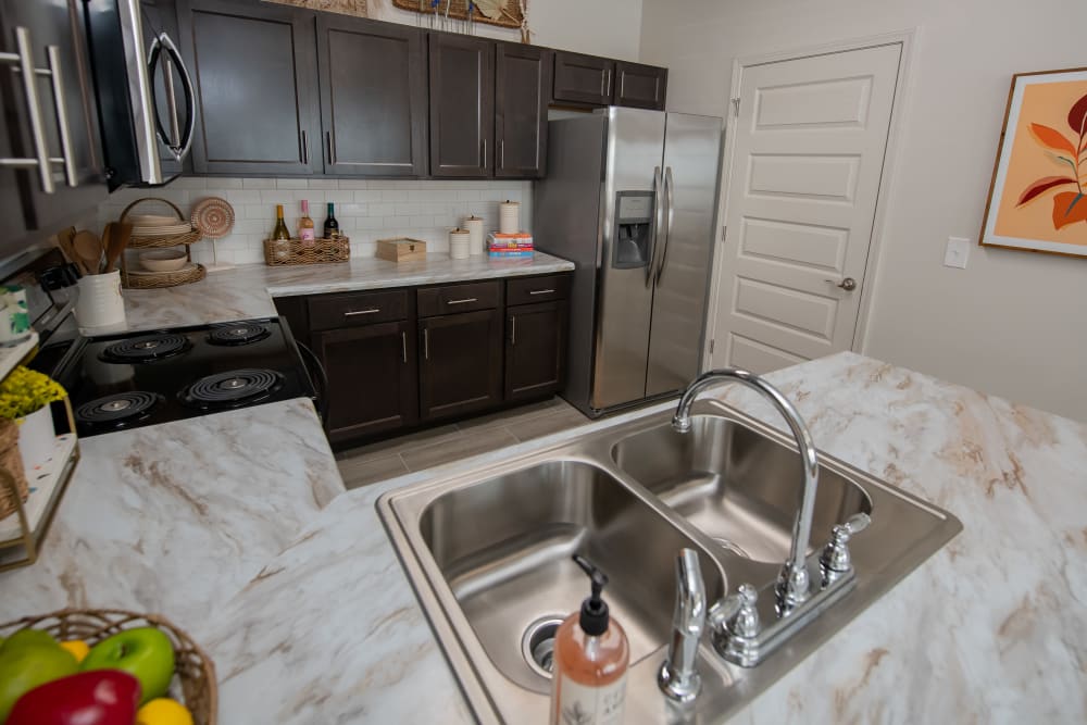 Gorgeous model home's kitchen with dark wood style cabinetry at 24Hundred Apartments in Oklahoma City, Oklahoma