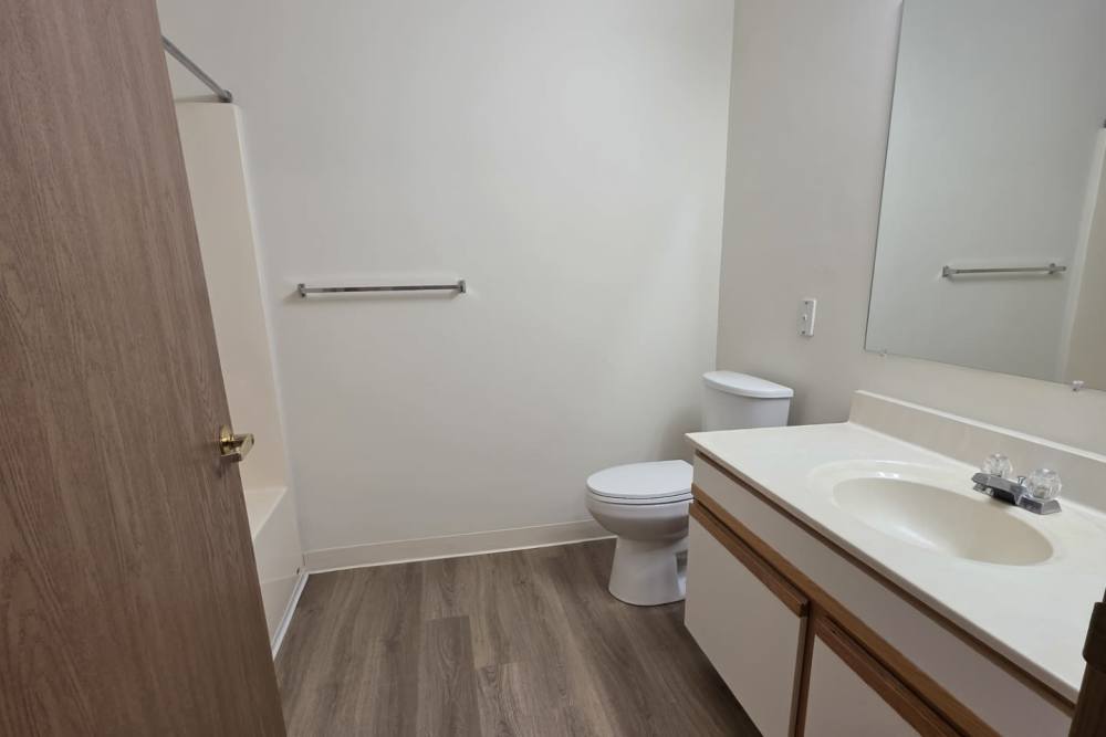 Upgraded bathroom with wood-style flooring at Cottages of Shippensburg in Shippensburg, Pennsylvania