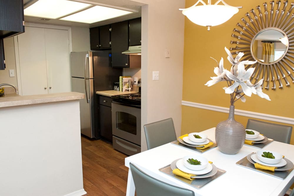 Dining area and kitchen with hardwood-style flooring and a warm yellow accent wall in a model home at Castlegate Collier Hills in Atlanta, Georgia