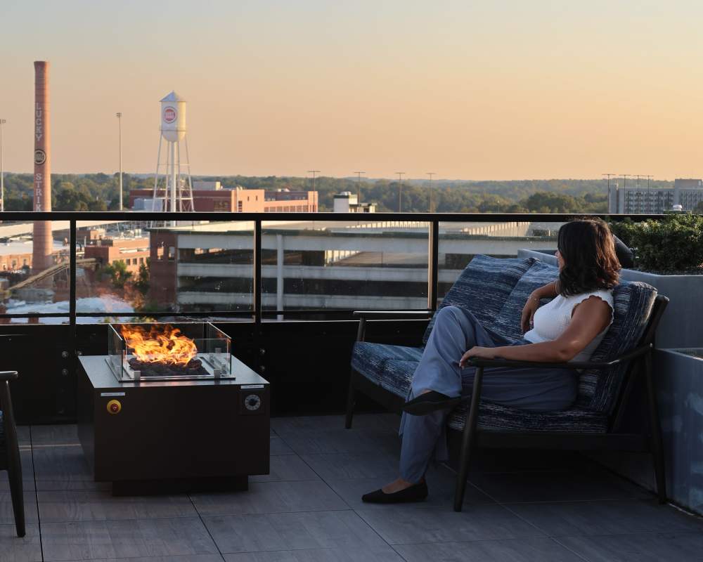 Resident sitting by a firepit on the roof deck at The Novus Apartments in Durham, North Carolina