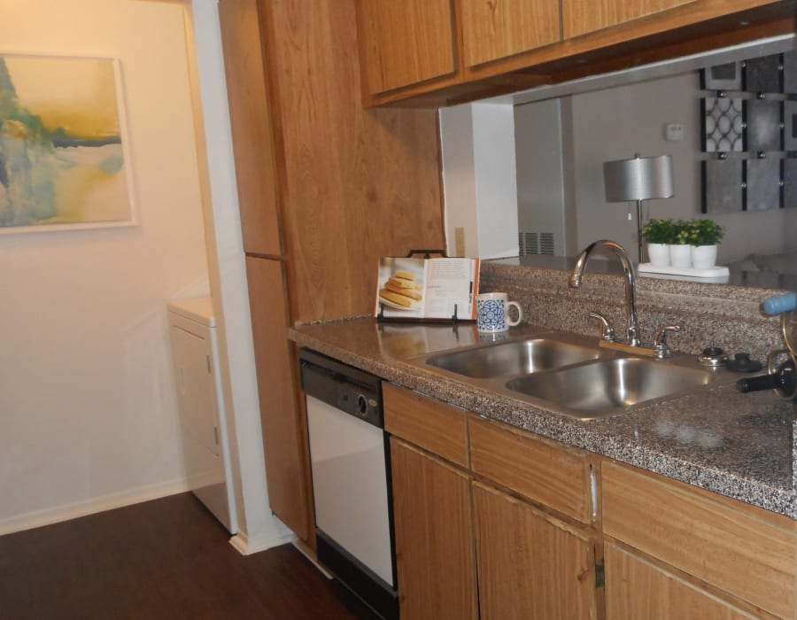Modern kitchen with hardwood flooring and an adjacent laundry room in a model home at Walden Pond in Houston, Texas