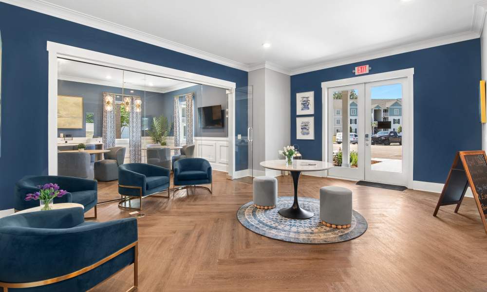 Modern lobby with wood-style flooring, blue walls, stylish seating, and large windows inviting natural light at Everett at Port Wentworth in Port Wentworth, Georgia