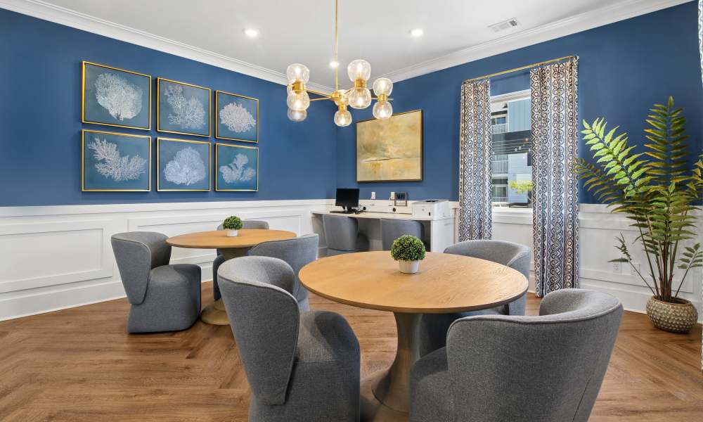Bright community workspace with modern decor, round wooden table, and comfortable gray chairs at Everett at Port Wentworth in Port Wentworth, Georgia