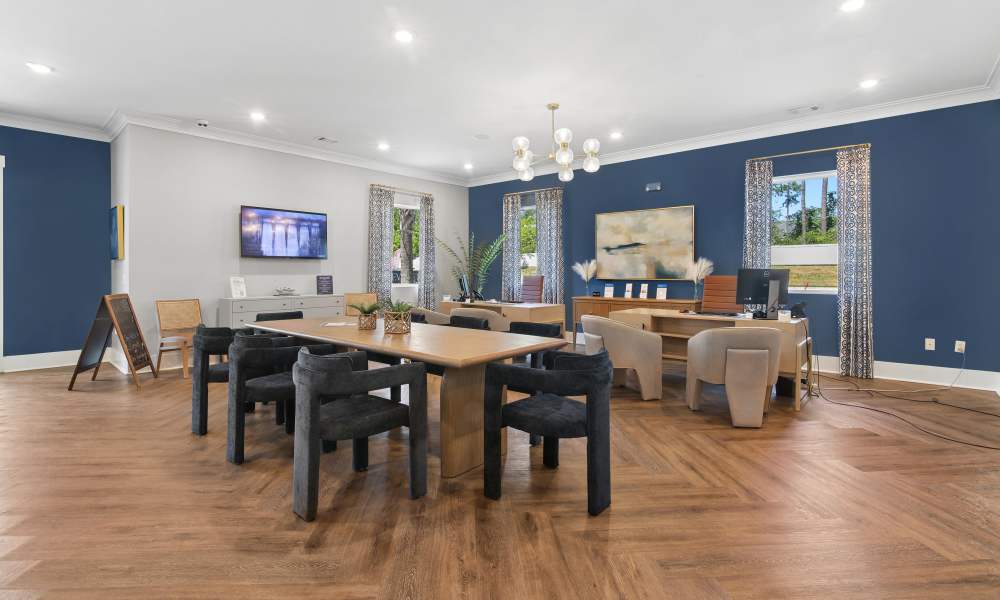 Modern community lounge with wood-style flooring, large windows, and stylish seating arrangements at Everett at Port Wentworth in Port Wentworth, Georgia