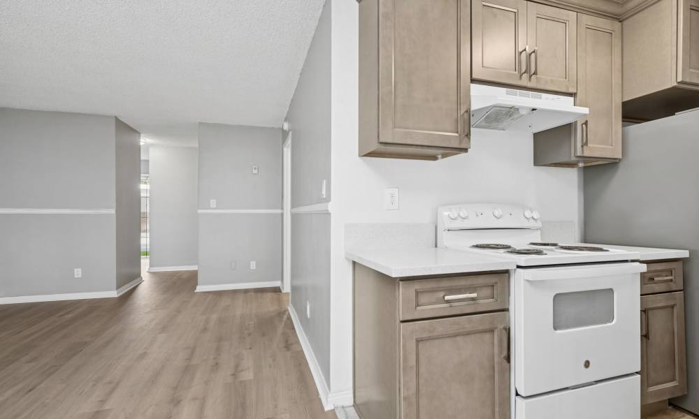 Modern kitchen with white appliances, wood cabinet and large window at Newland Garden Apartments in Garden Grove, California