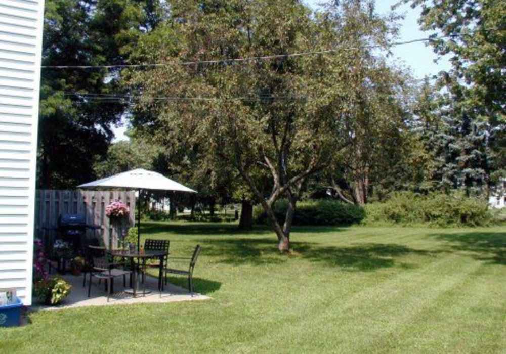 Shaded patio with dining set and greenery at Jefferson Manor Townhomes in Fairport, New York