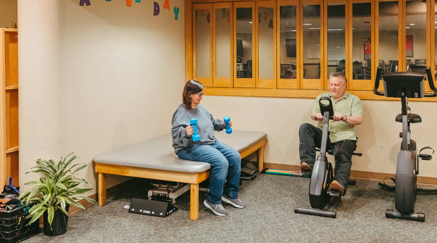 Residents lifting weights and using cardio equipment at Cascade Park Adult Day Health in Tacoma, Washington