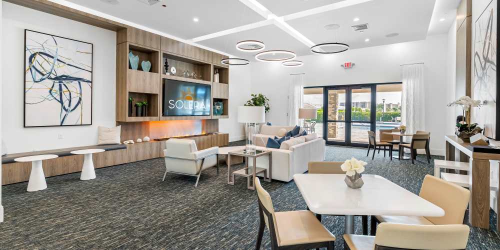 Bright community lounge with modern decor, comfortable seating, and large windows overlooking the outdoor space at Solera at Avalon Trails in Delray Beach, Florida