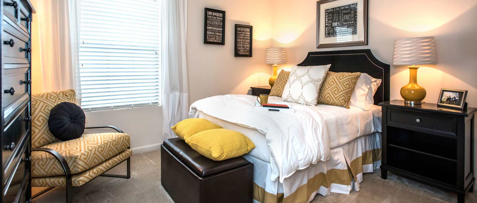 Cozy bedroom featuring a plush bed, decorative pillows, and a stylish armchair with patterned fabric at Stevens Creek Commons in Augusta, Georgia