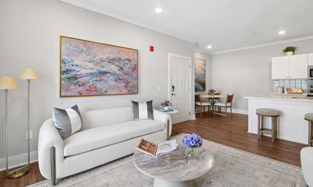 Bright living area with wood-style flooring, modern kitchen, and stylish artwork on the wall at Everett at Port Wentworth in Port Wentworth, Georgia