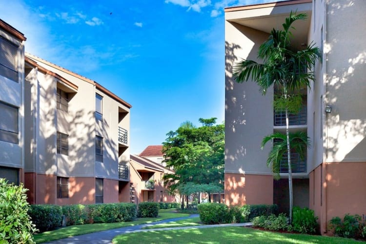 Exterior with lush landscaping and walking path at New Barn Apartments in Miami Lakes, Florida